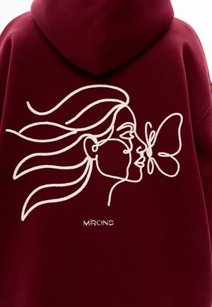 Bordowa bluza z kapturem z białym haftowanym wzorem przedstawiającym profil kobiety i motyla. Poniżej tekst "MIRONS." Miękka tekstura tkaniny.