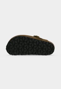 Sandale avec semelle extérieure en caoutchouc noir texturé à motif hexagonal et tige marron avec une bride réglable à boucle.