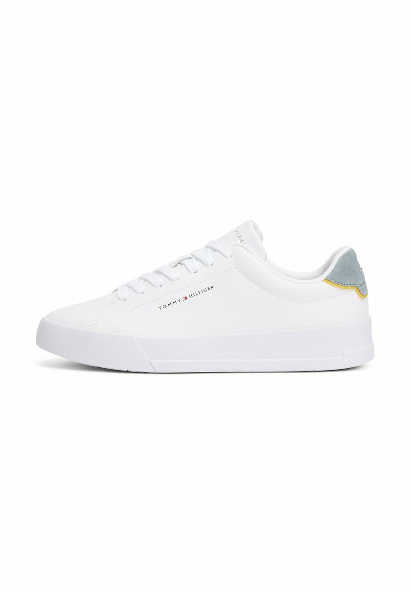 Białe sneakersy z gładką syntetyczną cholewką, sznurowanym zapięciem, szarym zamszowym akcentem na pięcie i żółtymi detalami z tyłu. Wytrzymała gumowa podeszwa.