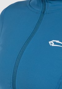 Blue athletic top made of smooth, stretchy fabric. Features a high collar, front zipper, and a white logo accent on the chest.