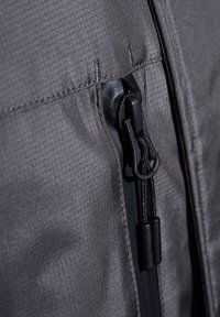 Czarna kurtka zapinana na zamek, wykonana z teksturowanej, lekkiej tkaniny, z czarnym zamkiem i sznurkiem przy otwarciu.