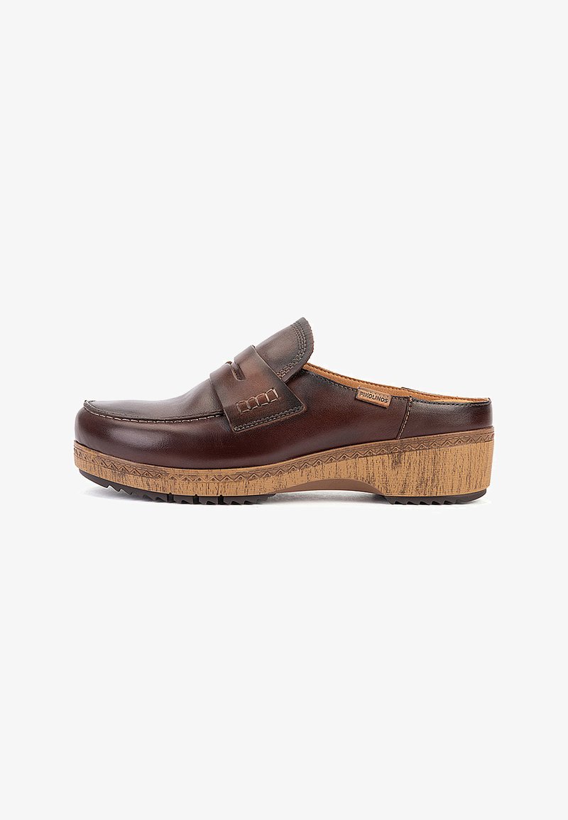 Sabot en cuir marron foncé à enfiler avec des détails cousus et une semelle compensée beige à motifs, étiqueté avec une petite étiquette Pikolinos.