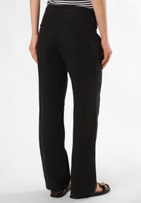 Black, wide-leg pants with a textured fabric, featuring two back pockets and a smooth waistband, paired with flat sandals.