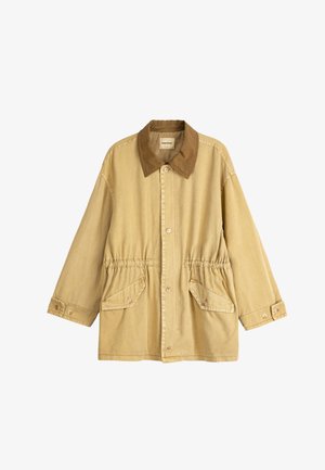 Veste beige avec col marron, fermeture frontale à boutons, taille élastique, poches à rabat inclinées, et poignets à boutons.