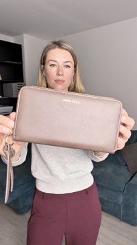 Pruun tehisnahast rahakott kuldse tõmblukuga ja logoga. Omab randmepaela, sujuvat tekstuuri, ristkülikukujulist vormi ja lihtsat disaini.