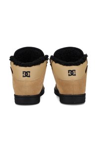 Braune Wildleder-Ankleboots mit einem schwarzen Kunstfellfutter, ausgestattet mit einer schwarzen Gummisohle und Logodetails an der Ferse.