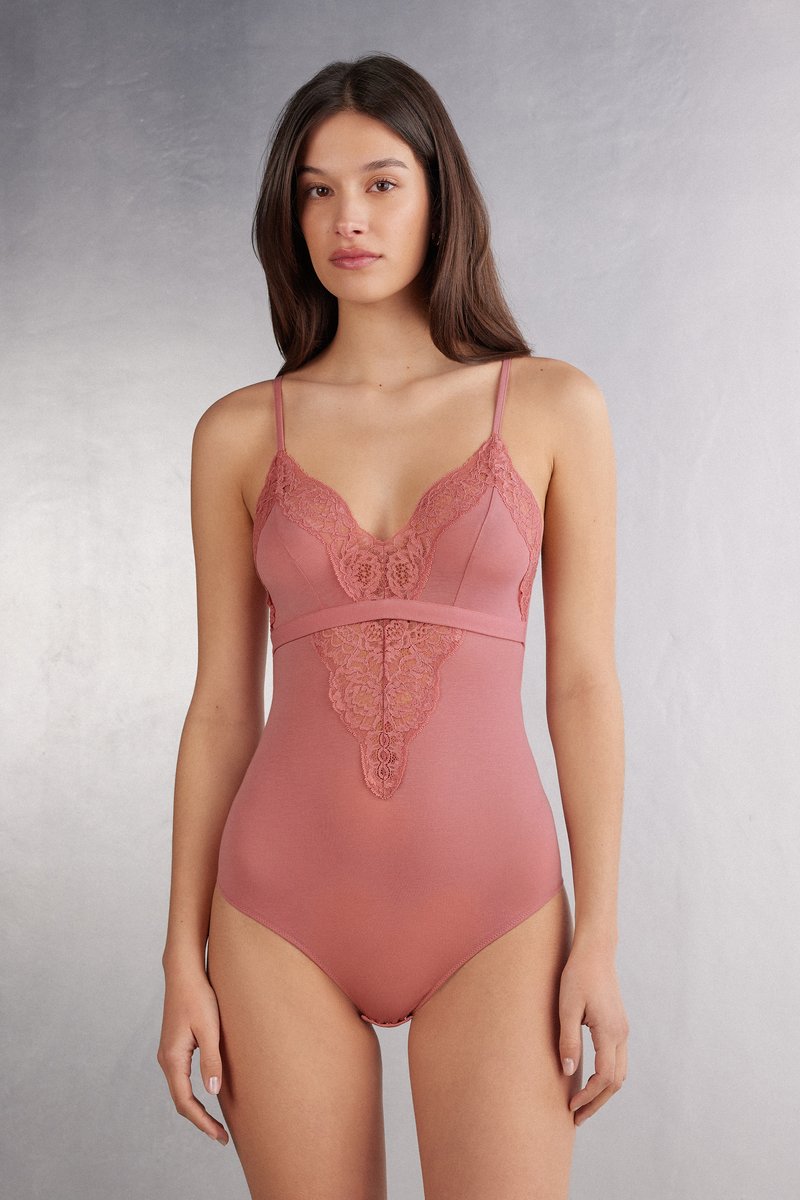 Roze bodysuit met kantafwerking langs de buste en het middenstuk, voorzien van verstelbare spaghettibandjes en een gladde, nauwsluitende textuur.