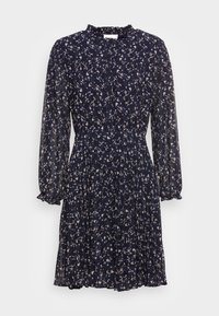 Navy kukkua mekko, joka on valmistettu kevyestä kankaasta. Mekossa on pitkät hihat, korkea kaula-aukko ja pleidetty hame, jossa on hillittyjä beigejä yksityiskohtia.