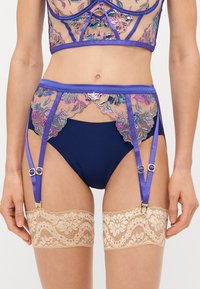 Set de lenjerie intimă bleu marin cu detalii transparente brodate în purpură și argint; include bretele pentru jartiere și ciorapi de dantelă până la coapse.