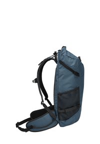 Zaino blu con un design slanciato, spallacci imbottiti e una tasca laterale in rete. Presenta hardware regolabile e un'esterno in tessuto resistente.