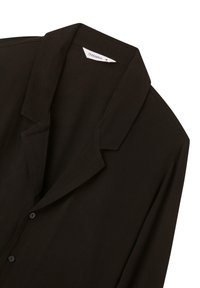 Blusa nera realizzata in tessuto leggero, con colletto a punta, chiusura a bottoni e silhouette morbida. Design semplice e monocromatico.