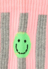 Tkanina dzianinowa z pionowymi szarymi paskami na różowym tle, z zielonym motywem uśmiechniętej buźki na środku.