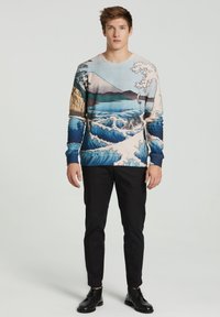 Puuvillane sviiter, millel on maastiku trükk lainetega, mägedega ja puudega sinise, beeži ja valge tooni kombinatsioonis. Kombineeritud mustade pükste jaotuses.