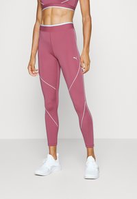 Leggings sportivi Puma di colore rosa polveroso con piping bianco. Tessuto liscio ed elasticizzato e vita alta, ideali per l'abbigliamento attivo.