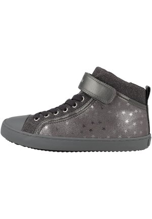 Zapatilla alta en gris oscuro con patrones de estrellas metálicas. Presenta una punta de goma y una correa de velcro para un ajuste seguro. Parte superior texturizada.