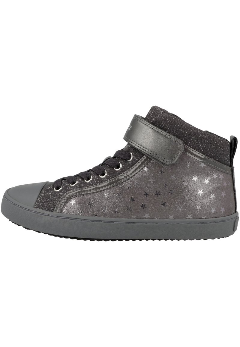 Zapatilla alta en gris oscuro con patrones de estrellas metálicas. Presenta una punta de goma y una correa de velcro para un ajuste seguro. Parte superior texturizada.