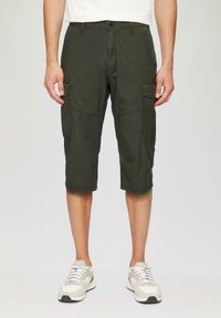 Cargo-Shorts aus dunkelgrünem Stoff, knielang, mit seitlichen Taschen, Reißverschluss und legerem Schnitt. Getragen mit hellgrauen Sneakers.