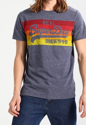 Mørkeblå T-shirt med korte ærmer i tekstureret stof med et farverigt vintage logo-design med røde, gule og grønne striber.