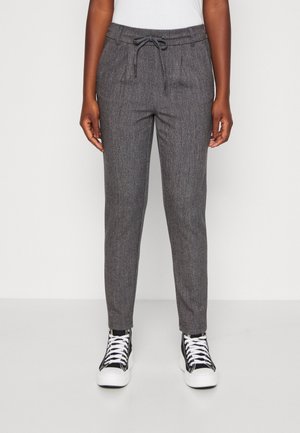 Grijze gewatteerde joggingbroek met een trekkoord in de taille, zijzakken en taps toelopende boorden, gecombineerd met zwart-witte hoge sneakers.