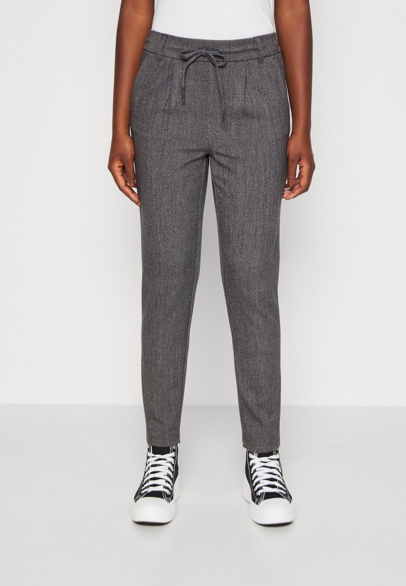 Grå mönstrade joggerbyxor med dragsko i midjan, sidofickor och tapered muddar, tillsammans med svarta och vita högskor.