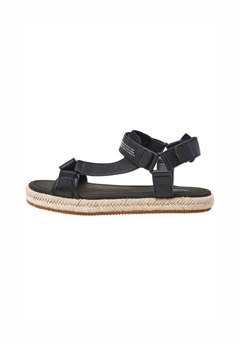 Musta nahkasaapas, jossa on espadrillo-tyylinen kudottu ina, säädettävät hihnat ja teksturoitu pohja mukavuutta varten.