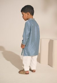 Lichtblauwe, gestructureerde kurta met een ruitpatroon, gecombineerd met witte broeken en bruine sandalen. De kurta heeft gedetailleerde manchetten.