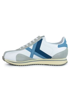 Zapatilla blanca con acentos en azul y gris, que presenta una parte superior de cuero suave, detalles en ante texturizado y una suela de goma con cordones tradicionales.
