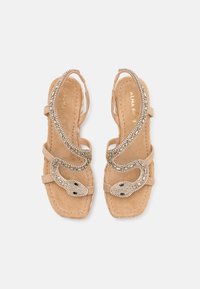 Sandali in suede beige con un design a forma di serpente, impreziositi da dettagli metallici e una texture a perline. Modello open-toe con cinturini sottili.