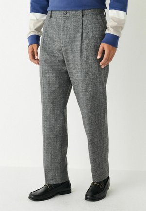 Grau karierte Hose aus strukturiertem Stoff, mit maßgeschneidertem Schnitt und zwei vorderen Taschen, kombiniert mit schwarzen Slippern.