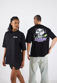 Sort oversized t-shirt med et panda grafik, stjerner og "Kakkoii" tekst på ryggen. Blødt stof, korte ærmer og afslappet pasform.