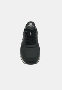 Baskets noires avec un dessus en synthétique lisse, dotées d'un bout rond, d'un col rembourré, d'accents blancs sur la semelle et de lacets noirs.