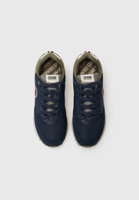 Navy blue sneakers with mesh and suede textures, featuring gray laces, a logo detail on the side, and a patterned insole.
