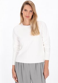 Pulover alb cu mâneci lungi, guler rotund și mansete cu dungi, asortat cu pantaloni gri deschis. Textură moale și design simplu.