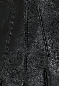 Zwarte leren handschoenen met zichtbare stiksels en een getextureerde afwerking. Het ontwerp bevat verhoogde naden langs de vingers.