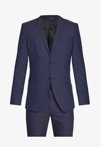 Veste de costume bleu marine avec deux boutons, revers crantés, poche poitrine simple et tissu texturé ; comprend un pantalon assorti visible en dessous.