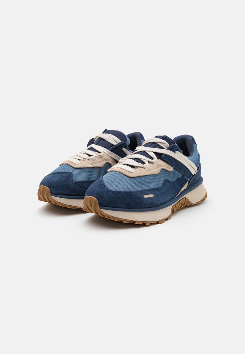 Blauwe sneakers van suede en mesh, met een gelaagd ontwerp, beige accenten, vetersluiting en een rubberen zool met een gestructureerd patroon.