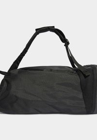 Sac de sport cylindrique noir en tissu texturé, doté de deux poignées ajustables et d'un compartiment zippé sur un côté.