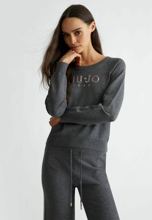 Pullover grigio in cotone con collo rotondo, caratterizzato da un logo decorato con strass e polsini a coste, abbinato a jogger grigi coordinati.