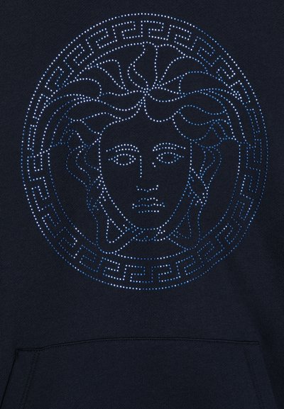 Sudadera navy con logo circular de Medusa, hecha de una tela con un patrón de tachuelas en azul claro y blanco, con acentos de borde de clave griega.