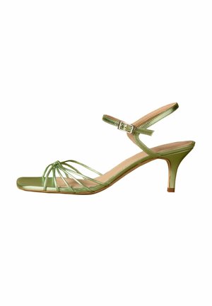 Green strappy open-toe sandal with a low heel and an adjustable ankle buckle strap on a white background.