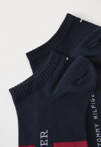 Chaussettes marine avec texture côtelée et accents rouges contrastants. Dotées d'un texte logo blanc sur le côté et d'un design de poignet renforcé.