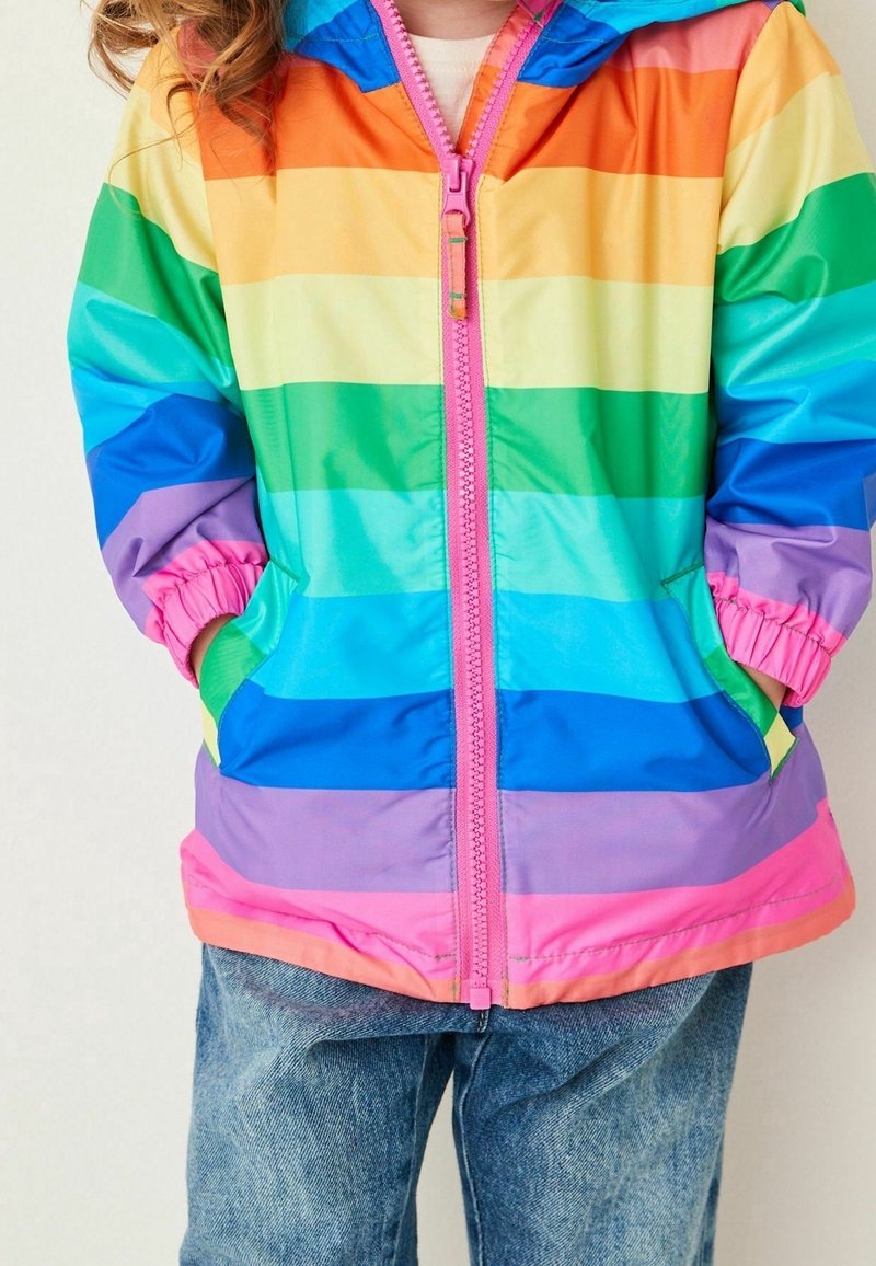 Veste légère à capuche colorée avec des rayures horizontales en orange, jaune, vert, bleu et rose. Dotée d'une fermeture éclair rose et de poignets élastiques.
