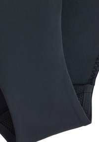 Černé sportovní legíny s hladkou texturou, které mají obepínající střih a síťovanou část na dolní části nohy pro lepší prodyšnost.