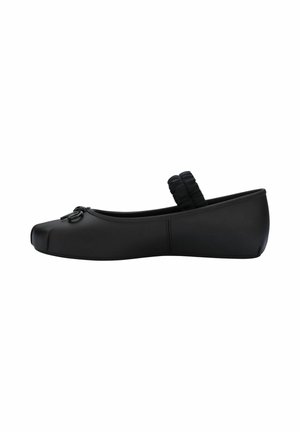 Scarpa piatta nera con punta quadrata arrotondata, cinturino elastico sul collo del piede e piccolo fiocco decorativo davanti.