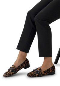 Mocassini con stampa leopardata in suede marrone e nero, con dettagli decorativi in metallo nero. Tacco a blocco basso e una texture liscia.