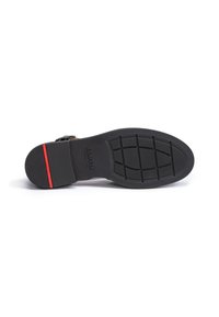 Black shoe sole featuring a textured surface with a grid pattern and a red accent stripe near the heel. Durable rubber material.