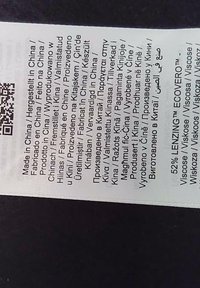 Étiquette d'entretien textile sur fond blanc avec un texte multilingue concernant l'origine du produit, la composition des matériaux et les instructions d'entretien.