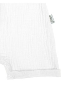 Biały kombinezon z muślinu o fakturowanym, pofałdowanym wzorze, z zapięciami na napy na dole oraz markową metką z boku.