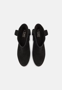 Crne antilop čizmice do gležnja s okruglim vrhom, bočnim petljama za lakše obuvanje i otisnutim logotipom na unutrašnjosti. Gladak materijal i minimalistički dizajn.