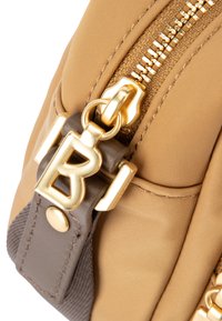 Borsa in nylon beige con zip e hardware dorati, dettagli in pelle marrone e una lettera "B" dorata prominente come elemento decorativo.